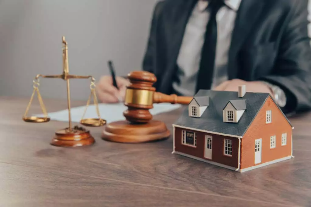 House model with gavel lawyer in background working at desk